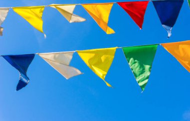 Çok renkli bayraklar mavi gökyüzüne karşı üçgen şeklinde şekillenir. Şehir sokak tatili teması için iyi bir geçmiş.