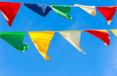 Çok renkli bayraklar mavi gökyüzüne karşı üçgen şeklinde şekillenir. Şehir sokak tatili teması için iyi bir geçmiş.