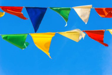 Çok renkli bayraklar mavi gökyüzüne karşı üçgen şeklinde şekillenir. Şehir sokak tatili teması için iyi bir geçmiş.