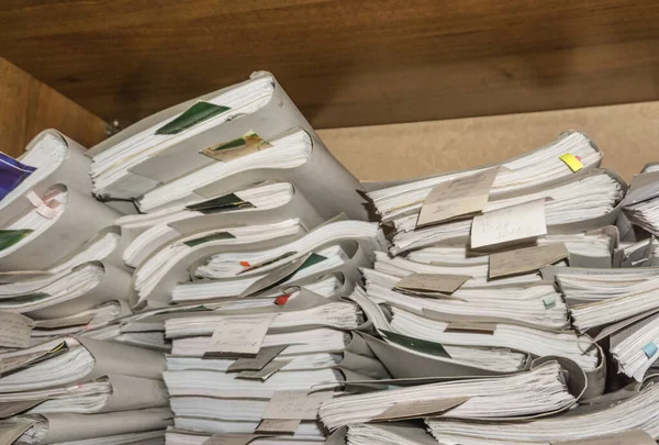 Paper documents stacked in archive. Documents on the shelves of archive room. Office shelves in the closet full of files