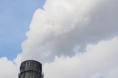 Mavi gökyüzüne karşı fabrikalardan tüttüren borular. Sigara fabrikasının bacasına yakın çekim. ekoloji