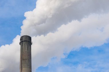 Mavi gökyüzüne karşı fabrikalardan tüttüren borular. Sigara fabrikasının bacasına yakın çekim. ekoloji