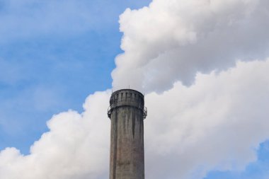Mavi gökyüzüne karşı fabrikalardan tüttüren borular. Sigara fabrikasının bacasına yakın çekim. ekoloji