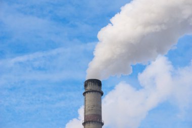 Mavi gökyüzüne karşı fabrikalardan tüttüren borular. Sigara fabrikasının bacasına yakın çekim. ekoloji