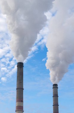 Mavi gökyüzüne karşı fabrikalardan tüttüren borular. Sigara fabrikasının bacasına yakın çekim. ekoloji