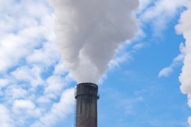 Mavi gökyüzüne karşı fabrikalardan tüttüren borular. Sigara fabrikasının bacasına yakın çekim. ekoloji