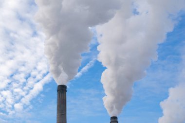 Mavi gökyüzüne karşı fabrikalardan tüttüren borular. Sigara fabrikasının bacasına yakın çekim. ekoloji