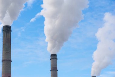 Mavi gökyüzüne karşı fabrikalardan tüttüren borular. Sigara fabrikasının bacasına yakın çekim. ekoloji