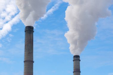 Mavi gökyüzüne karşı fabrikalardan tüttüren borular. Sigara fabrikasının bacasına yakın çekim. ekoloji