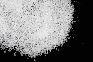 Siyah arka plana beyaz deniz tuzu döküldü. Siyah arkaplanda şeffaf çakıl taşları