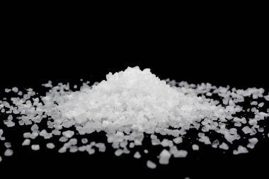 Siyah arka plana beyaz deniz tuzu döküldü. Siyah arkaplanda şeffaf çakıl taşları