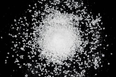 Siyah arka plana beyaz deniz tuzu döküldü. Siyah arkaplanda şeffaf çakıl taşları