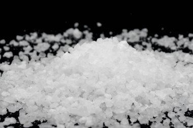 Siyah arka plana beyaz deniz tuzu döküldü. Siyah arkaplanda şeffaf çakıl taşları