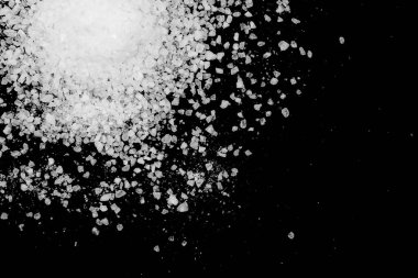 Siyah arka plana beyaz deniz tuzu döküldü. Siyah arkaplanda şeffaf çakıl taşları