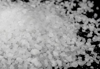 Siyah arka plana beyaz deniz tuzu döküldü. Siyah arkaplanda şeffaf çakıl taşları