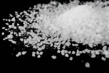 Siyah arka plana beyaz deniz tuzu döküldü. Siyah arkaplanda şeffaf çakıl taşları