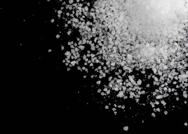 Siyah arka plana beyaz deniz tuzu döküldü. Siyah arkaplanda şeffaf çakıl taşları