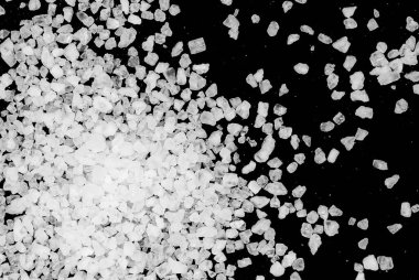 Siyah arka plana beyaz deniz tuzu döküldü. Siyah arkaplanda şeffaf çakıl taşları