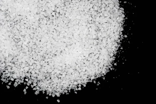 Siyah arka plana beyaz deniz tuzu döküldü. Siyah arkaplanda şeffaf çakıl taşları