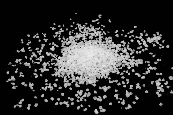 Siyah arka plana beyaz deniz tuzu döküldü. Siyah arkaplanda şeffaf çakıl taşları