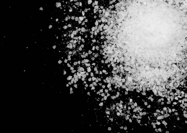 Siyah arka plana beyaz deniz tuzu döküldü. Siyah arkaplanda şeffaf çakıl taşları
