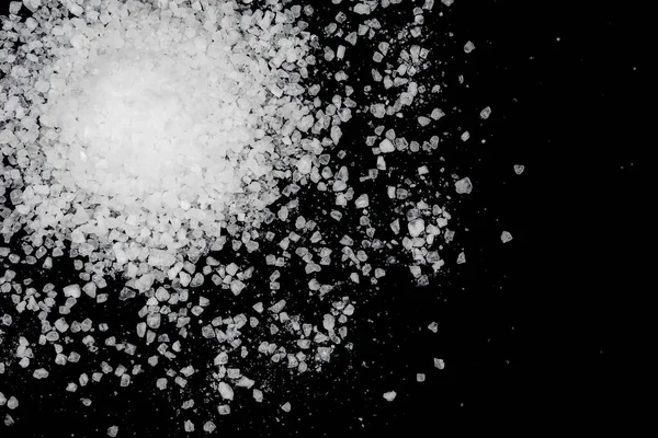 Siyah arka plana beyaz deniz tuzu döküldü. Siyah arkaplanda şeffaf çakıl taşları