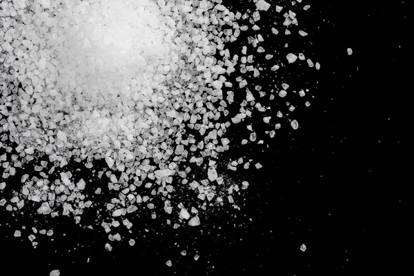 Siyah arka plana beyaz deniz tuzu döküldü. Siyah arkaplanda şeffaf çakıl taşları