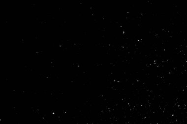 Siyah arka planda beyaz lekeler ve izler var. Beyaz bulanıklık ve dalgalanmalar. Kar yağışı, soyutlama