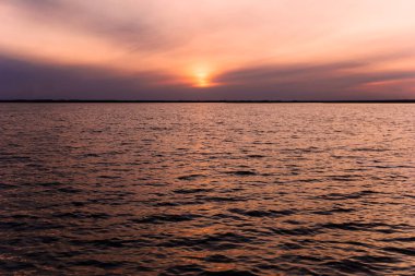Suda gün batımı yansıması, günbatımında su yüzeyinin arka planı, gün batımında kızıl şafak ya da gün batımında göl manzarası, altın gün doğumu ya da su ve gökyüzünde bir günbatımı.