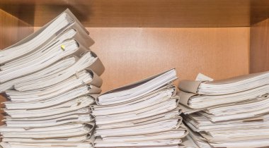 Arşivde birikmiş eski kağıt belgeler. Belgeler arşiv odasının raflarında. Ofis rafları dosyalarla dolu dolapta.