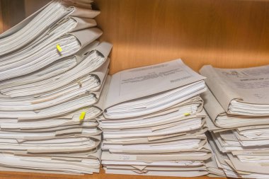 Arşivde birikmiş eski kağıt belgeler. Belgeler arşiv odasının raflarında. Ofis rafları dosyalarla dolu dolapta.