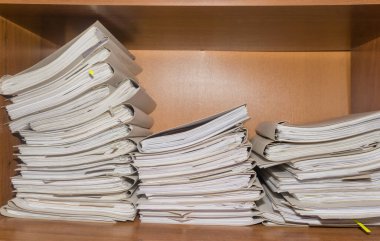 Arşivde birikmiş eski kağıt belgeler. Belgeler arşiv odasının raflarında. Ofis rafları dosyalarla dolu dolapta.