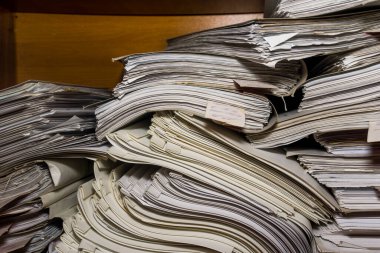 Arşivde birikmiş eski kağıt belgeler. Belgeler arşiv odasının raflarında. Ofis rafları dosyalarla dolu dolapta.