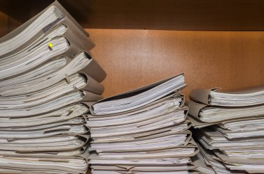 Arşivde birikmiş eski kağıt belgeler. Belgeler arşiv odasının raflarında. Ofis rafları dosyalarla dolu dolapta.