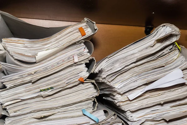 Old paper documents stacked in archive. Documents on the shelves of archive room. Office shelves in the closet full of files