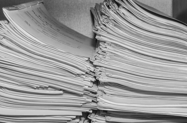 Бумажные документы хранятся в архиве. Документы на полках архивной комнаты. Полки в шкафу, заполненные файлами. черно-белое фото