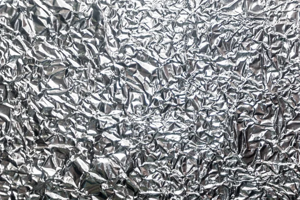 Silver wrinkled foil background texture, crumpled aluminum foil, abstract shiny background