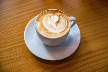 Tahta bir masada bir fincan sıcak kapuçino..