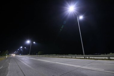 Geceleri sokak lambaları olan boş kırsal yol. 