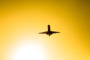 Turuncu gün batımında uçan uçak silueti