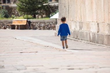 Küçük çocuk eski duvarların arasında tek başına yürüyor.. 