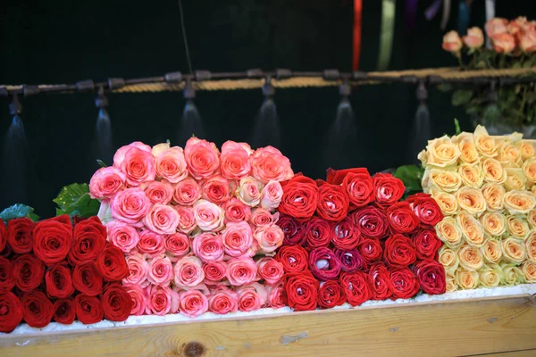 Bouquets of different varieties of roses are sold in the street market.