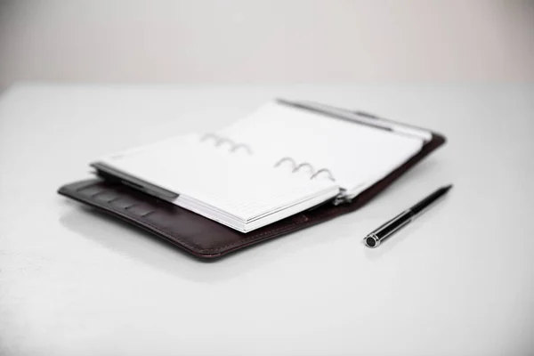 Blank open notebook with pen on white background.