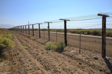 Mavi gökyüzü arka planında dikenli tel çit. 