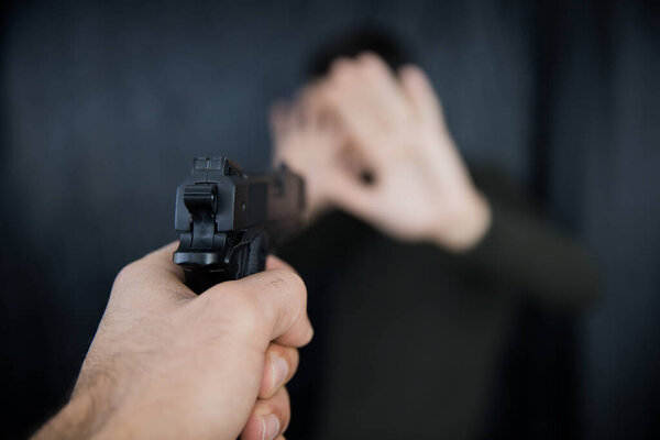 Close up of male hands with a gun shooting. 