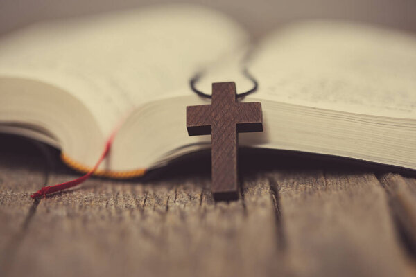Wooden cross and book on tabl