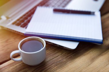 Klavyesinde kalem, üstünde kahve olan not defteri.