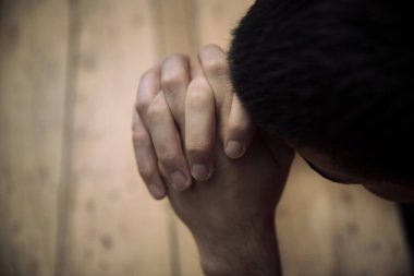 Erkek elleri, tahta bir masada dua ederken katlanır.