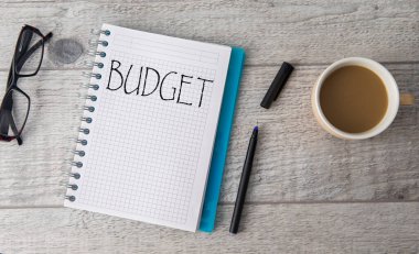 Not defterine yazılmış bütçe metni ve masada kahve!