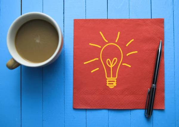 Glühbirne Auf Serviette Mit Kaffee Auf Blauem Tisch — Stockfoto